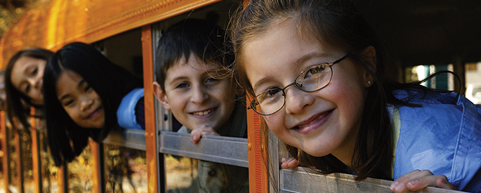 four students looking through window of school bus