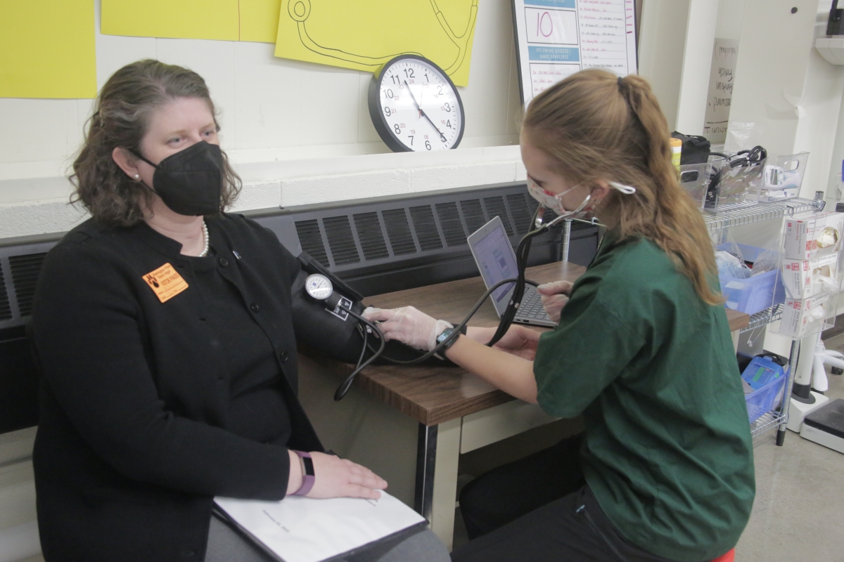 Superintendent has her vitals taken by student.