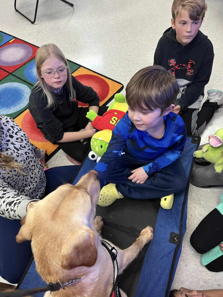 Spartacus the English lab therapy pup poses with some of his elementary school friends
