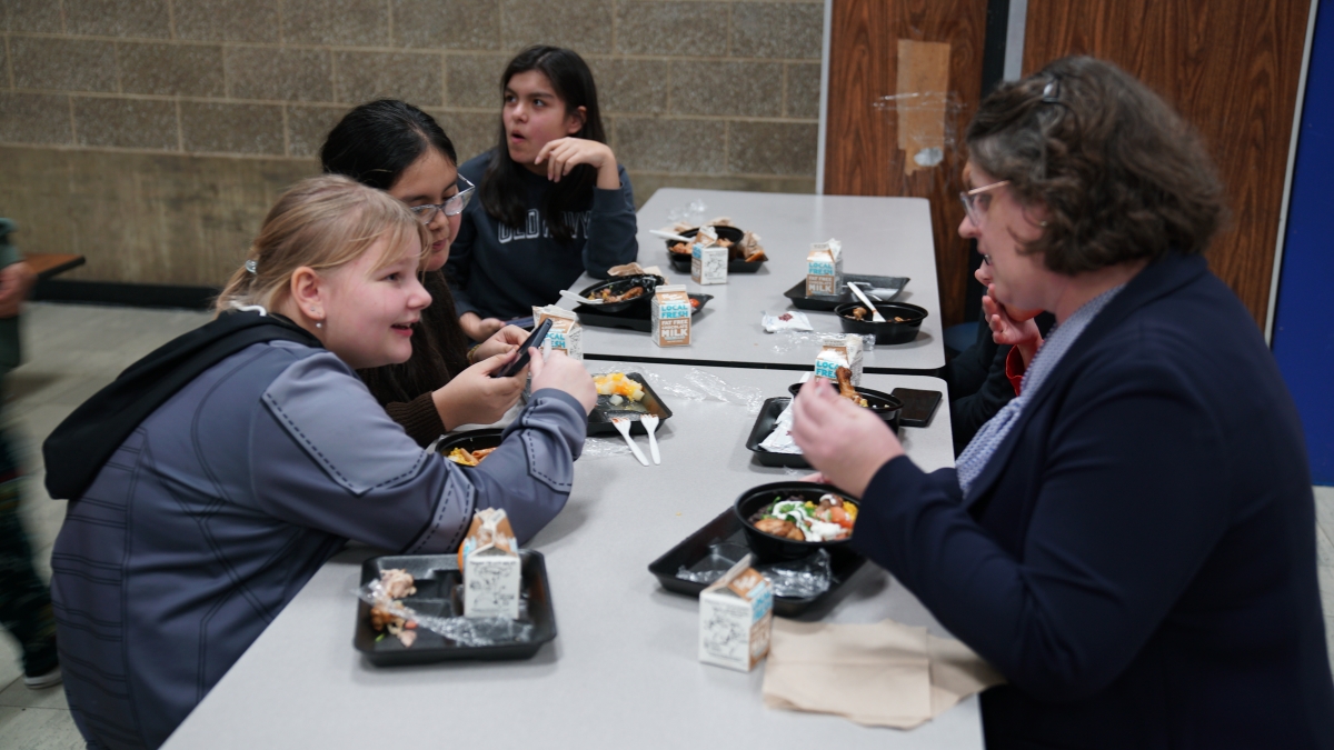 State Superintendent Dr. Underly sits with students at their lunch table