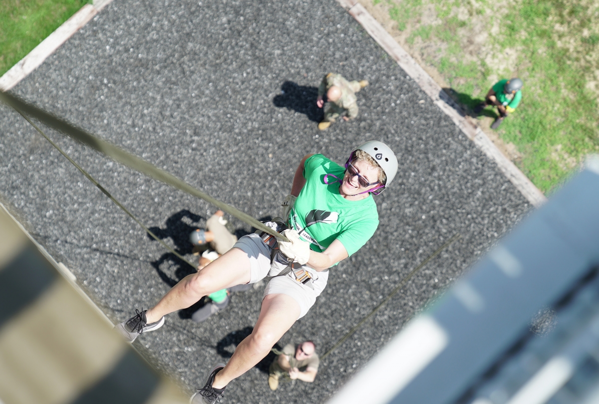 A participant of the Educator Leadership Rendezvous climbs up the rope climb at Fort McCoy.
