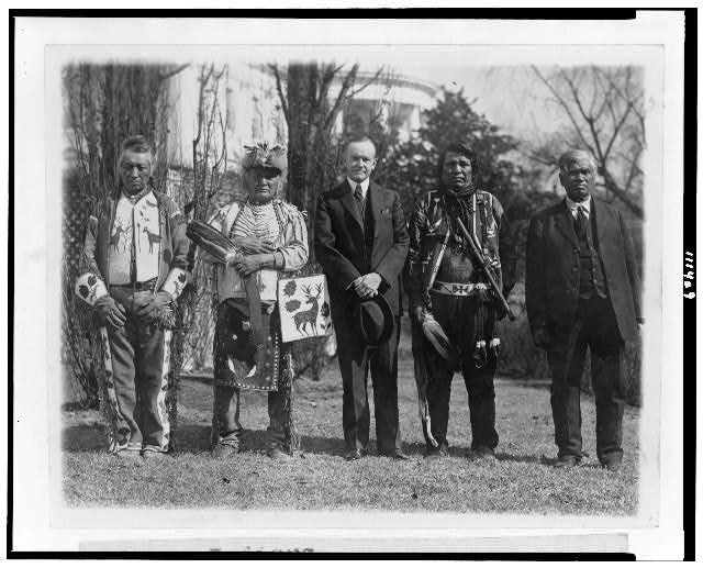 President Calvin Coolidge posed with Natives, possibly from the Plateau area in the Northwestern United States, near the south lawn of the White House