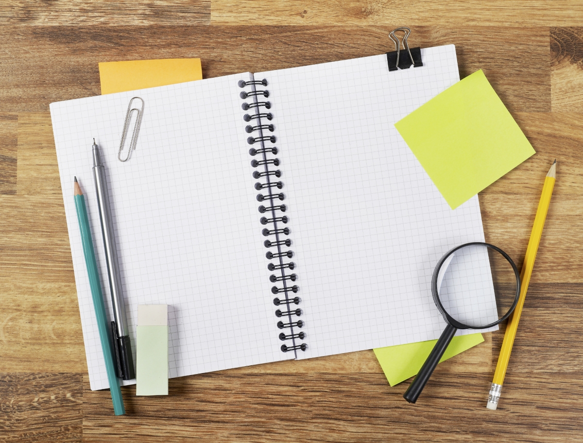 Photo of an open notebook with various office supplies.
