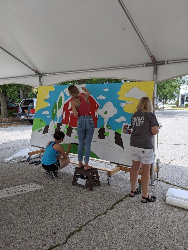 Plymouth community members work on a children's mural for the local library.