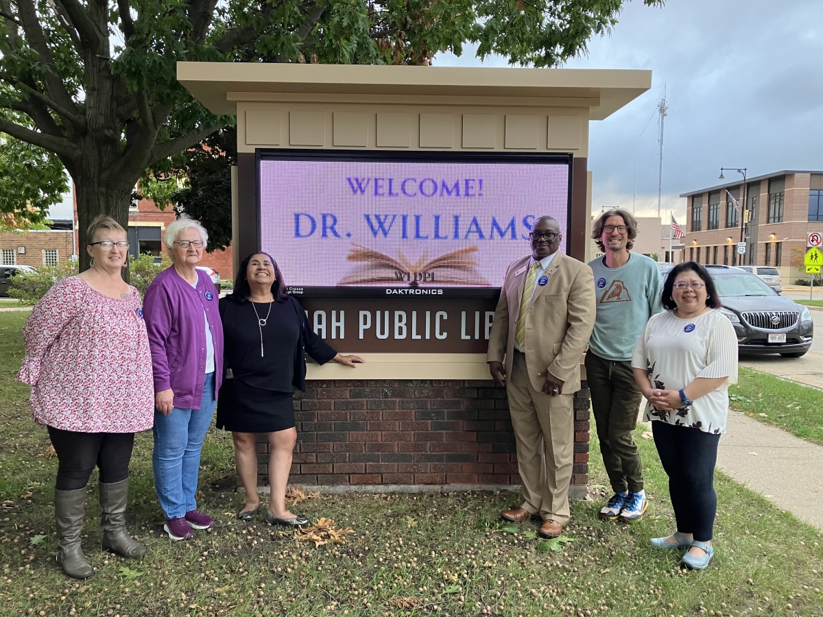 Tomah Public Library staff with Dr. Williams in front of welcome sign