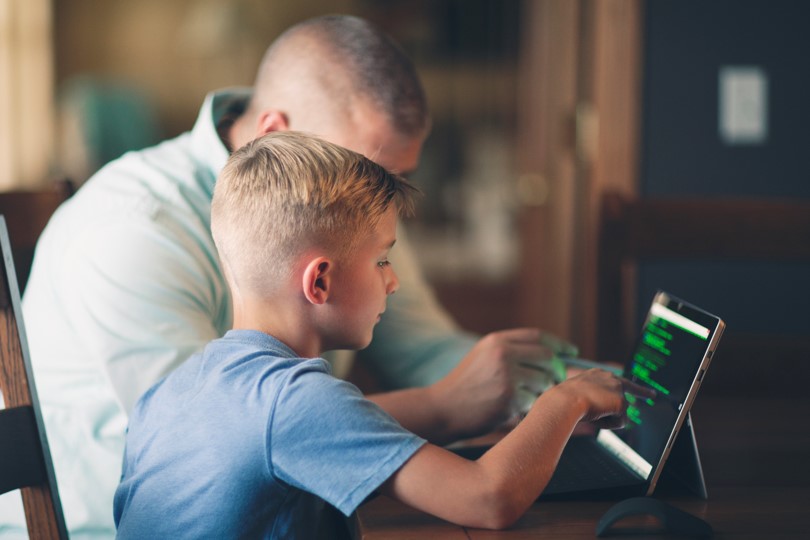Adult helping boy on computer